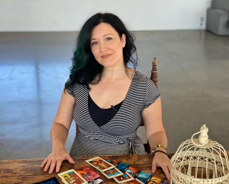 Larissa Taróloga sentada à mesa, com cartas de tarô espalhadas à sua frente